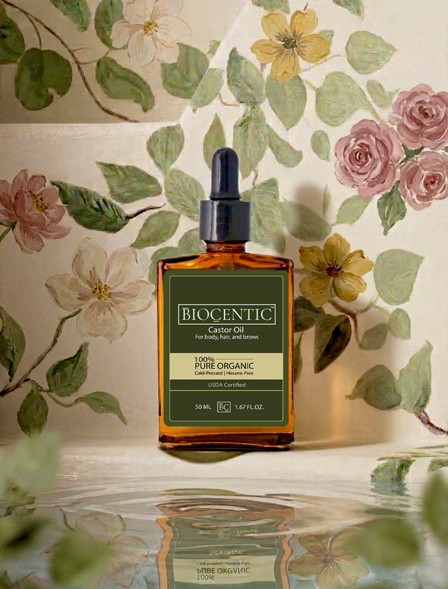 50 mL amber glass bottle of BIOCENTIC castor oil, reflected on a pale surface.